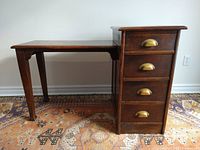 Front view of desk showing top surface, left work surface with tapered legs, and right pedestal with four drawers