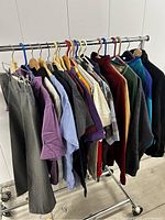 Photo showing a rack with 10 different casual clothing items including shirts, sweaters, and pants in mixed colors and styles.