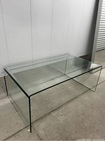 Front view of clear glass waterfall coffee table on concrete floor
