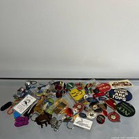 Photo showing an assortment of keychains and pins laid out on a flat surface with clear view of items and detail