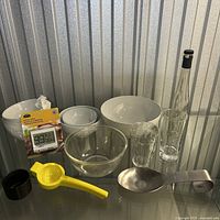 Full lot of kitchen items displayed on glass shelf including bowls, glasses, timer, utensils