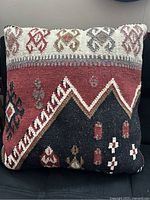 Front view of the large Kilim cushion showing the red, black, white, and beige geometric and floral woven patterns.