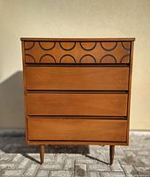 Front view of walnut dresser showing four drawers and carved circular motif on top drawer
