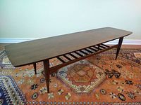 Full-angle view showing surfboard shape, tapered legs and open slatted shelf.