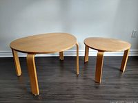 Both nesting tables side by side against wall on dark flooring, showing overall shape and size difference
