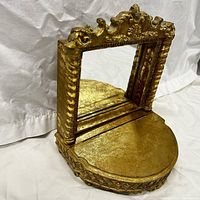 Front angle view of the gold-tone vanity mirror box showing the mirror upright and semi-circular base with decorative edge
