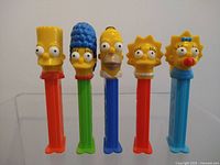 Front view of all five Simpsons PEZ dispensers standing upright.