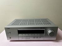 Front view of Yamaha AVR-1700 AV Receiver showing control buttons, display screen, and volume knob.