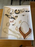 Top view of assorted earrings, bracelets, and necklaces showing amber, coral, and silver items.