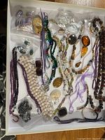 Photo of assortment of beads and jewelry components showing multiple strands and loose beads including carved pendants and glass beads