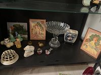 Wide shot of the collection displaying various vintage decorative items including framed prints, ceramic figurines, and a glass dolphin compote.