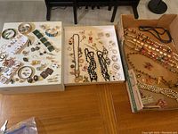 Overview of jewelry spread across three trays and a table showing various necklaces, bracelets, brooches, and earrings.