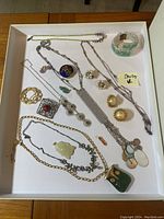 Costume jewelry assortment including necklaces, earrings, pendants, and bracelet. One necklace labeled sterling silver.