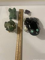 Four carved fog fetish figurines of different stones with ruler for scale