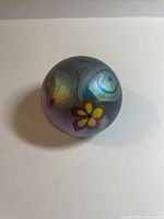 Top view showing the iridescent finish and flower design on the glass paperweight.