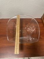 Top view of Simon Pearce clear glass bowl with ruler measuring length around 11 inches.