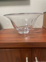 Side view of clear glass Simon Pearce Shelburne bowl sitting on wooden surface, showing flared shape and circular foot.
