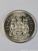 Front side of silver-colored Canadian 50 cents coin from 1962 showing the coat of arms and inscriptions.