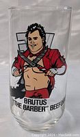 Photo of clear glass showing cartoon image of wrestler Brutus The Barber Beefcake with scissors and text on front