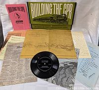 Photo of the collection spread out showing booklets, vinyl record, map, newspaper clippings and handwritten notes.