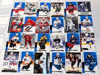 Photo of 24 hockey cards laid out in a 6x4 grid showing different NHL players in various poses and teams.