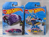 Two new Hot Wheels cars in packaging, including 'Believe' and 'Motosaurus' models.