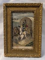 Art print showing a historical scene with two riders and a wagon, framed in detailed gold frame.