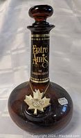 Front view of brown glass bottle with black and gold Entre Amis label and gold maple leaf medallion.