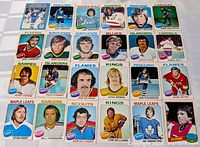 Wide view of 26 vintage hockey cards laid out showing various NHL teams and players from the 1970s.