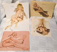 Four vintage pin-up style nude art prints by Vargus displayed laid flat on a white cloth surface