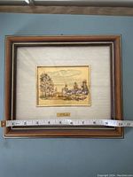 Front view of the framed chromolithograph measuring approximately 9 inches wide showing the brown and gold wooden frame with beige mat.