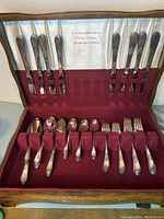 Full view of the 52 piece silver plated flatware set laid out inside the burgundy felt-lined tarnish resistant box showing knives, forks and spoons neatly arranged.