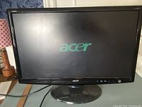 Front view of Acer 23-inch monitor powered on displaying the Acer logo on screen with control buttons and power button visible on lower right bezel.
