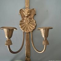 Front view of brass wall sconce showing cherub and double candle holders
