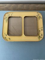 Top view showing the yellow enamel double photo frame with floral accents and dual photo openings.