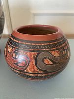 Front view of round handmade pottery vase with intricate black and reddish-brown Cherotega-style painting.