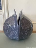 Side view of large glossy grey-blue pottery vase with split central opening, showing texture and shape
