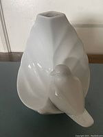 Front and side angle showing porcelain leaf-shaped vase with bird attached