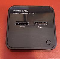 Top view of black MAIWO device showing dual NVMe M.2 SSD bays labeled 'Source' and 'Target', supporting M key and B&M key SSDs.