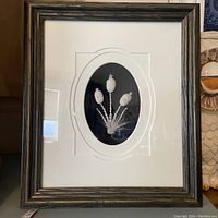 Full view of framed tufted artwork showing three cat-tail plants on black background with white mat and dark wood frame.