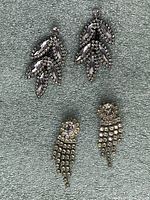 Two pairs of rhinestone pierced earrings laid flat on a grey textile background, showing front design.