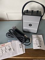 Photo showing the WinBridge S98 portable PA system alongside the Pyle dynamic handheld microphone with cable and user manuals.