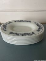 Stack of six oval Pyrex side plates showing the rim decoration and shape.