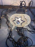 Oval handmade mosaic glass lamp globe, white and mirrored star pattern with brass fittings and long hanging cord. Viewed hanging vertically with chain untangled.