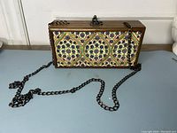 Front view of wood box purse showing patterned fabric panel and attached dark metal chain strap.