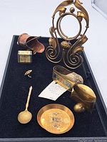 Full view of all brassware items including Art Nouveau frame, shoe ashtray, letter holder, spoon, dish, small box, and thimble