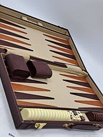 Full view of open backgammon set showing case, checkers in two colors, multiple dice, and doubling cubes.