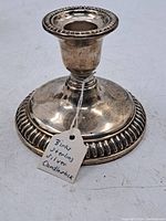 Photo of Birks weighted sterling silver candlestick with ribbed base detail and a tag indicating its description.