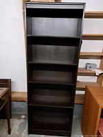 Front view of the vintage dark brown bookshelf, showing five shelves and some wear on the surface.