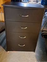 Front view of the black chest of drawers showing four drawers with silver curved handles